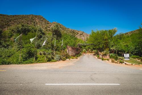 an empty road with flags on the side of a mountain at De Poort Country Lodge in Oudtshoorn