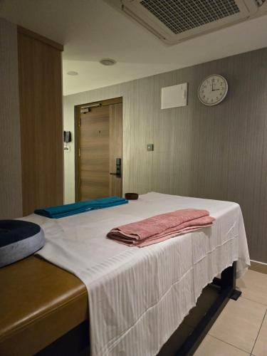 a bed with a white blanket and a clock on the wall at MoonBasa Boutique Hotel and Spa Infopark , Kakkanad in Cochin