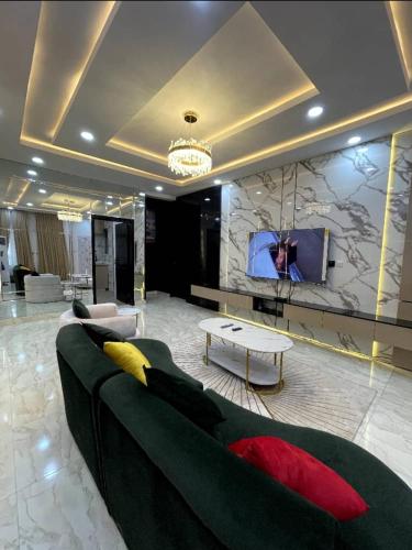 a living room with a green couch and a tv at De-Luxe Haven Apartment in Lekki