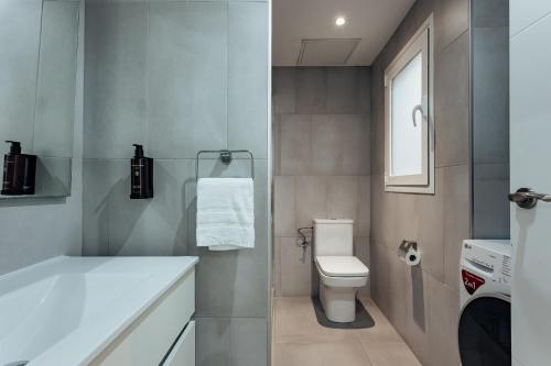 a bathroom with a white toilet and a sink at Vibe Apartments by Olala Homes in Hospitalet de Llobregat