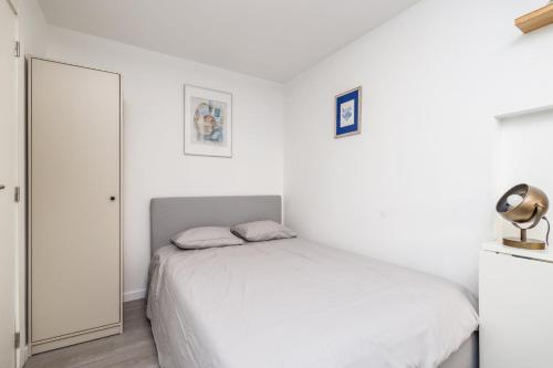 Un dormitorio blanco con una cama y un espejo. en GuestReady - Minimalist Studio In Downtown Lisbon, en Lisboa