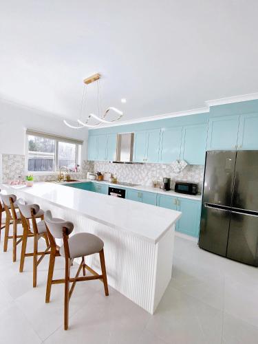 a kitchen with a white counter and blue cabinets at Modern Family Oasis - 4BR, Free Parking, Steps to Shops & Train in Melbourne