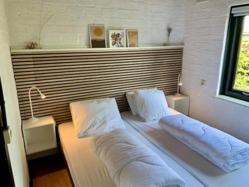 a bed with pillows on it in a room at Bungalow in dune area of Sint Maartenszee in Sint Maartenszee