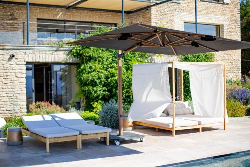 un patio avec deux chaises et un parasol dans l'établissement 8-bedroom luxury villa with pool, à Gordes