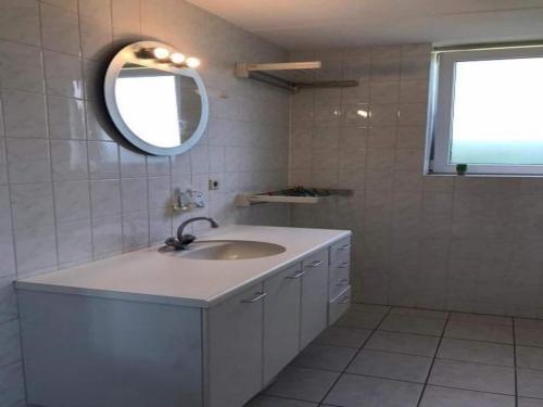 a white bathroom with a sink and a mirror at Comfortable 6-person holiday home in Sint Maartenszee