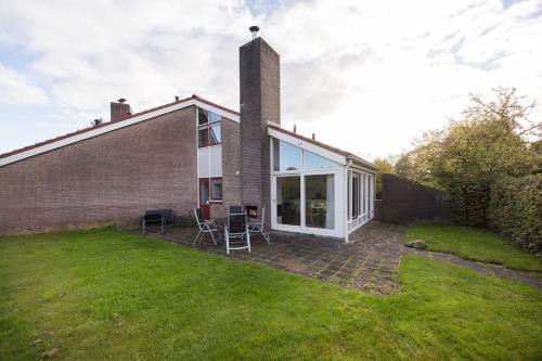 a house with a large window and a lawn at Kruisbek I Chic Huisje met Riante Tuin in Zwiggelte