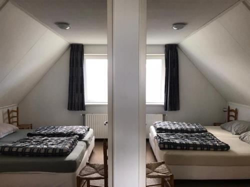 two beds in a attic room with two windows at Comfortable 6-person holiday home in Sint Maartenszee