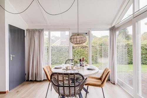 a dining room with a table and chairs and a large window at Kruisbek I Chic Huisje met Riante Tuin in Zwiggelte