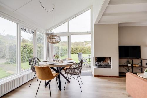 a dining room with a table and chairs and a fireplace at Kruisbek I Chic Huisje met Riante Tuin in Zwiggelte