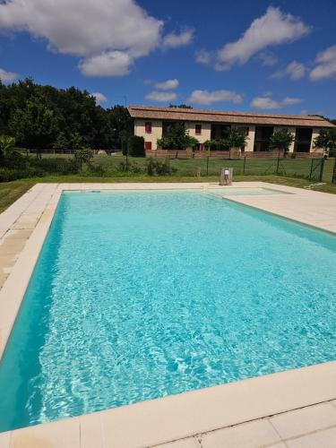 une piscine bleue avec une maison en arrière-plan dans l'établissement Gite du Hêtre Pardaillan, à Pardaillan