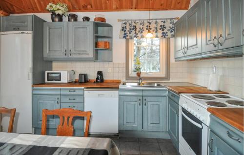 a kitchen with blue cabinets and a white refrigerator at 3 Bedroom Pet Friendly Home In Tived in Tived