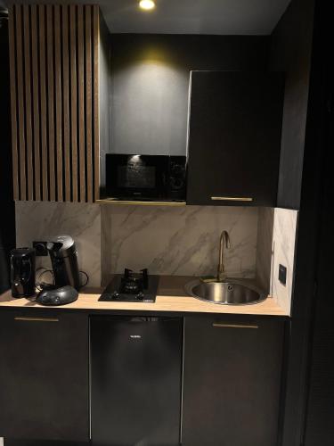une petite cuisine avec un évier et un micro-ondes dans l'établissement Love Room Balneo Menton, à Menton