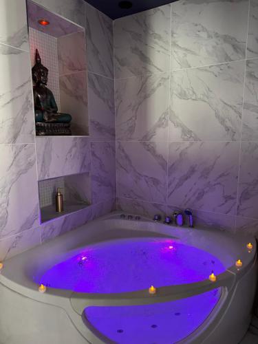 La salle de bains est pourvue d'une baignoire avec un éclairage violet. dans l'établissement Love Room Balneo Menton, à Menton