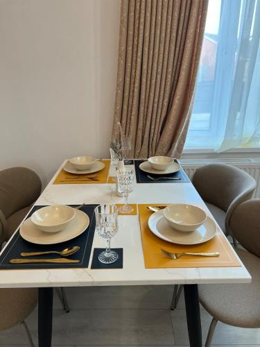 a dining table with two plates and glasses on it at The Place with king beds, Ensuite Bathrooms, Close to Airport and Free Parking in Wythenshawe