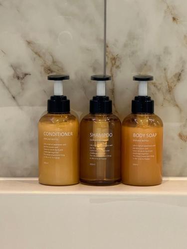 three bottles of soap sitting on a shelf at The Place with king beds, Ensuite Bathrooms, Close to Airport and Free Parking in Wythenshawe