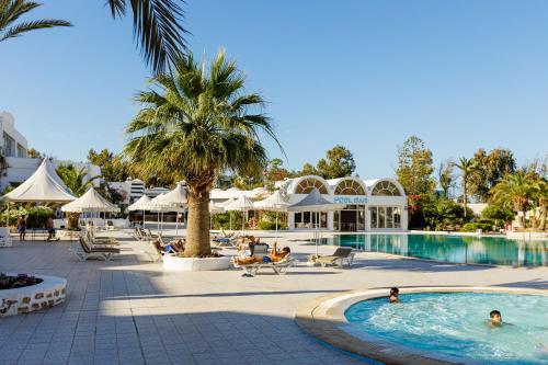 a pool at a resort with people sitting around it at Iris Hotel & Thalasso in Taguermess