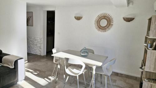 une salle à manger avec une table et des chaises blanches dans l'établissement Appartement LE BOIS FLOTTE, à Saintes-Maries-de-la-Mer