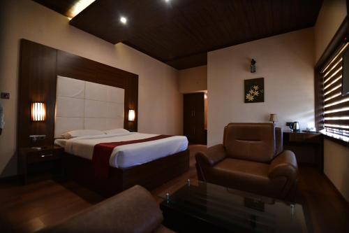 una habitación de hotel con una cama y una silla en Garuda Luxury Bungalow, en Trichūr