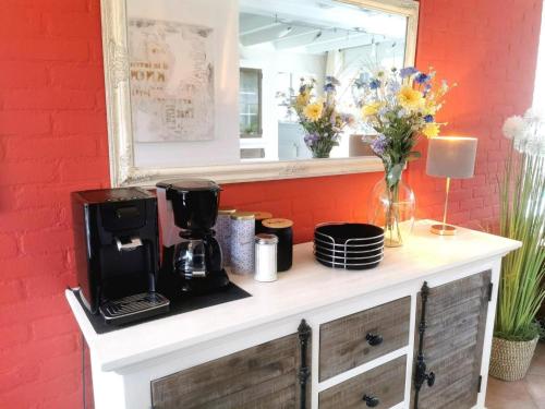 a counter with a coffee maker and flowers on it at Inviting bungalow with private garden in Sint Maartenszee