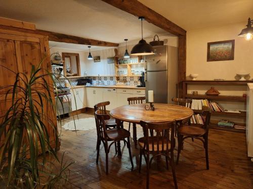 une cuisine avec une table, des chaises et un réfrigérateur dans l'établissement Maison de village médiéval surplombant les méandres de la loire, à Saint-Maurice-sur-Loire