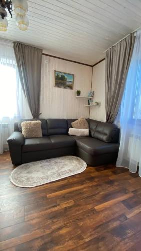 a living room with a black leather couch and a rug at Five House in Skhidnitsa