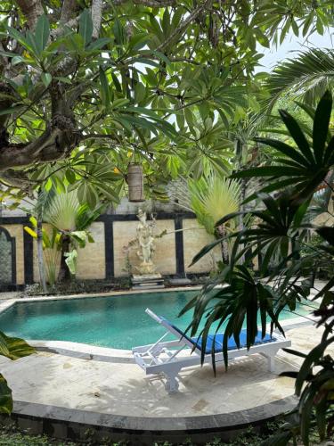 a swimming pool with a chair next to a palm tree at Bungalow Geringsing in Candidasa