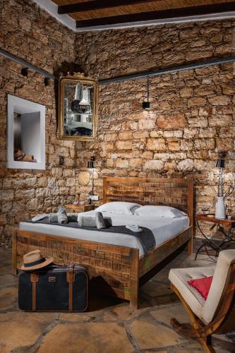 a bedroom with a bed and a stone wall at Oinoessa Traditional Boutique Guest Houses in Lofou