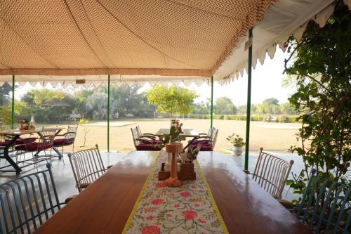 a long wooden table and chairs in a pavilion at Astroport Sariska Treetop by Eight Continents in Tehla