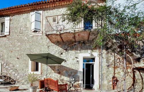 un parasol vert assis devant un bâtiment dans l'établissement Cozy Home In Saint-Nazaire-Daude, à Saint-Nazaire-dʼAude