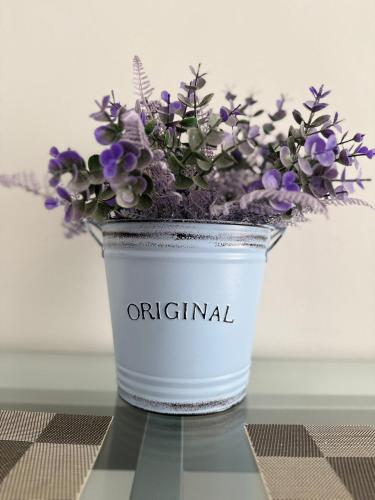 a white vase with purple flowers on a table at Apartamento Vega in Baena