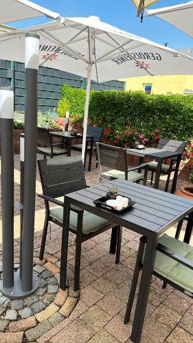 a picnic table and chairs under an umbrella at Hotel Restaurant Germania in Neuwied