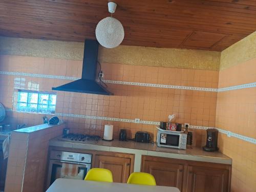 a kitchen with yellow chairs and a stove and a microwave at ti kaz Éléanord in Saint-Louis