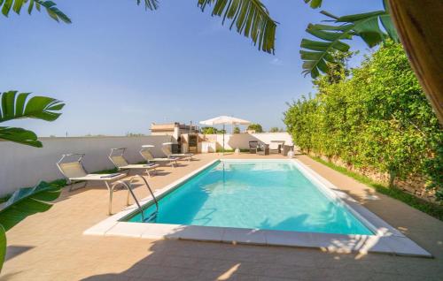 a swimming pool on a patio with chairs next to a house at Queen's Bay in Porto Palo