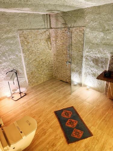 a room with a shower and a rug on a wooden floor at My Cave Suites in Nevsehir
