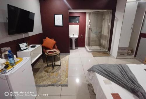 a bathroom with a bedroom with a shower and a television at Fresh Ideas GuestHouse in Soshanguve