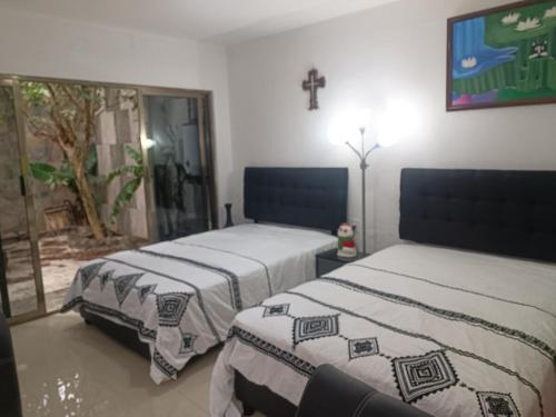 deux lits dans une chambre avec une croix sur le mur dans l'établissement Bonita residencia Casa Vera, à Río Blanco