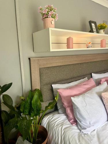 a bedroom with a bed with pink and white pillows at The Peace House in Pietermaritzburg
