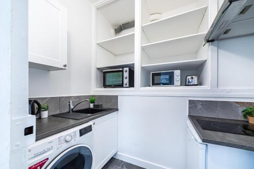 une cuisine avec des armoires blanches et une laveuse et une sécheuse dans l'établissement Studio équipé, gare à 200m, entre Versailles et SQY, à Saint-Cyr-lʼÉcole