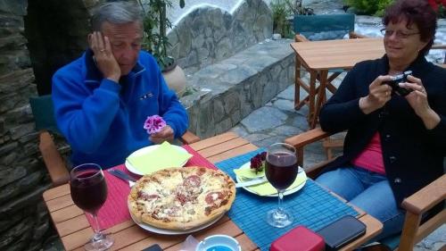 two people sitting at a table with a pizza at Gioma Hotel in Agia Galini