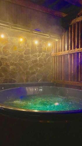 a large hot tub in a room with a stone wall at Five House in Skhidnitsa