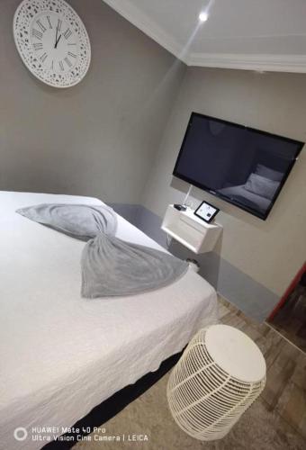 a bedroom with a bed and a clock on the wall at Fresh Ideas GuestHouse in Soshanguve