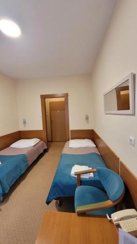 a room with two beds and a chair in it at Geovita Dąbki in Dąbki