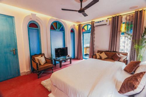 a bedroom with a bed and a tv and some windows at Bhagvatam by the Ganges in Shivpuri
