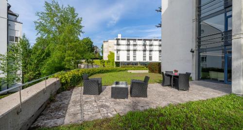 a patio with chairs and a table and a building at PLAZA INN Stuttgart-Ditzingen in Ditzingen