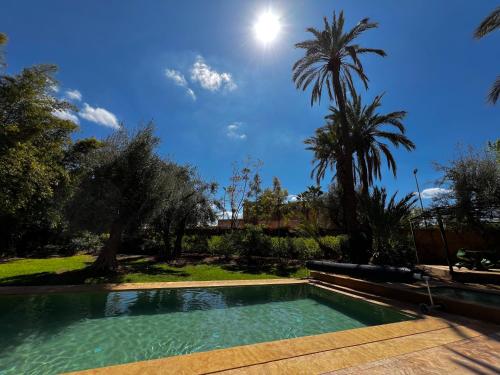 a swimming pool in a yard with palm trees at Villa kasbah de luxe, piscine et jacuzzi chauffés, jardin tropical in Marrakech