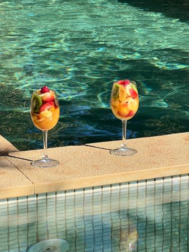 two glasses of fruit in front of a swimming pool at Villa kasbah de luxe, piscine et jacuzzi chauffés, jardin tropical in Marrakech