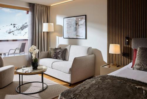 a hotel room with a bed and a couch at ROBINSON ALPENROSE Zürs in Zürs am Arlberg