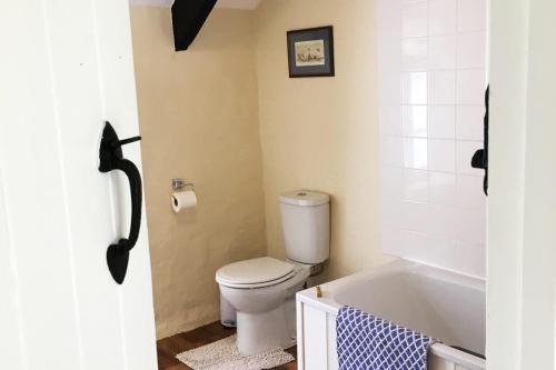 a bathroom with a toilet and a bath tub at Courtyard Cottage with hot tub and walled garden in Hubberston