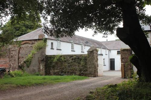 a white building with a stone wall next to a road at Courtyard Cottage with hot tub and walled garden in Hubberston