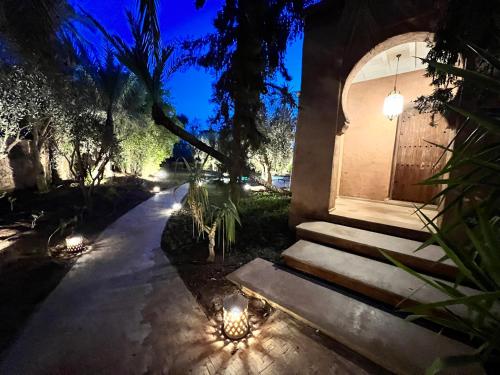 a house with a door and lights on the sidewalk at Villa kasbah de luxe, piscine et jacuzzi chauffés, jardin tropical in Marrakech